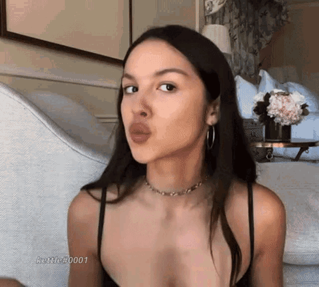 a woman is blowing a kiss while sitting on a couch in a room .