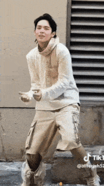 a man in a white sweater and khaki shorts is dancing on a street