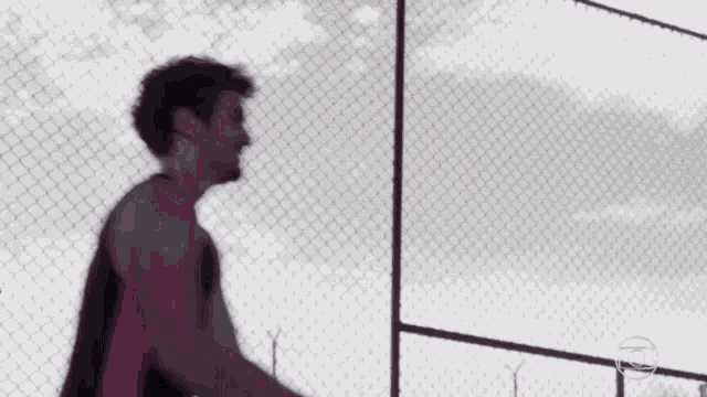 a blurry picture of a man and a woman holding hands behind a chain link fence