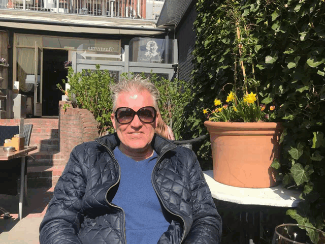 a man wearing sunglasses is sitting in front of a building that says ' savannah '