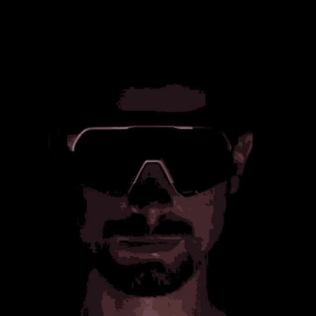 a man with a beard wearing a pair of sunglasses in the dark .