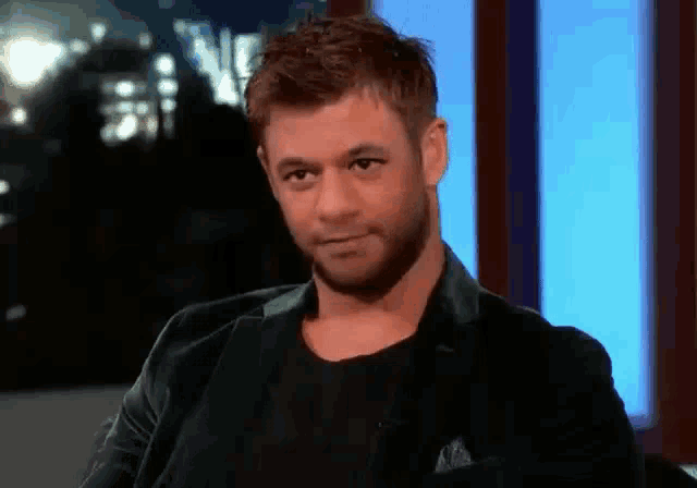 a man with a beard is wearing a black jacket and a black shirt