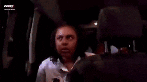 a woman is sitting in the back seat of an airplane talking to another woman .
