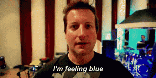 a man in a black shirt is talking to the camera and saying `` i 'm feeling blue '' .