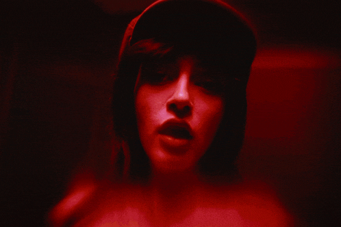 a woman wearing a hat is covering her face with her hands in front of a red background