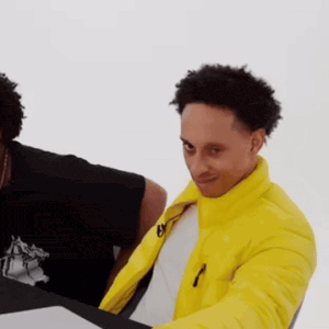 a man in a yellow jacket is sitting at a table with another man