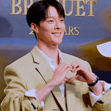 a man in a yellow jacket making a heart shape with his hands
