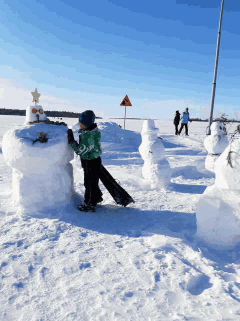a snowman with a star on top is being built by a young boy
