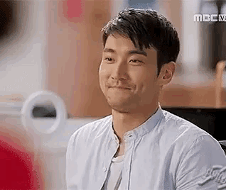 a man in a white shirt is smiling and looking at the camera .