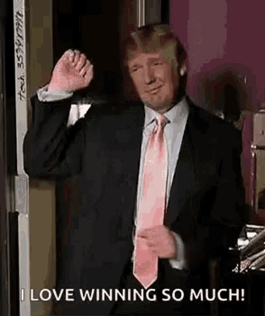 donald trump is wearing a suit and tie and making a fist .