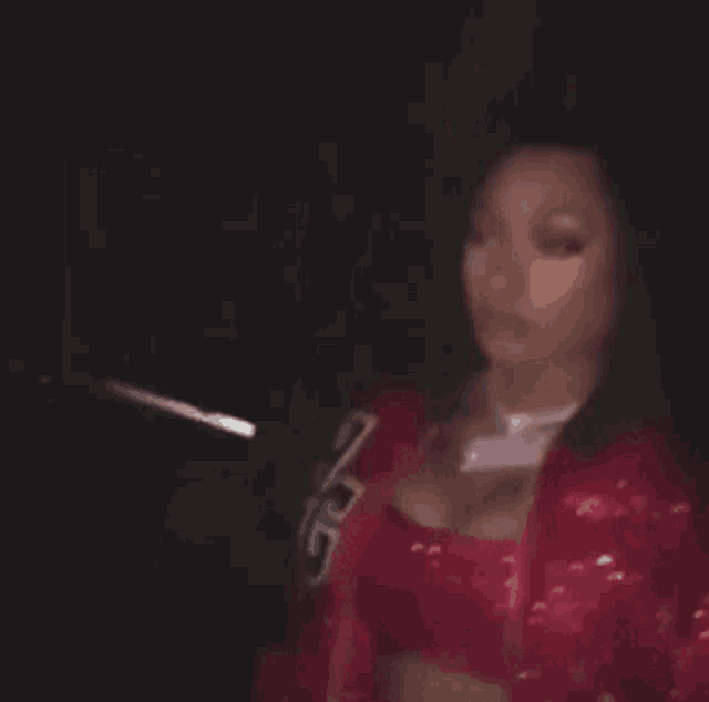 a woman wearing a red jacket and a red crop top is standing in a dark room .