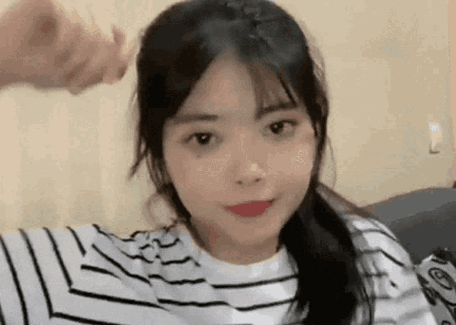a girl in a striped shirt is taking a selfie while sitting on a couch .