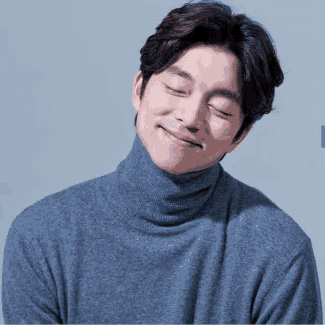 a man wearing a gray turtleneck sweater is smiling with his eyes closed