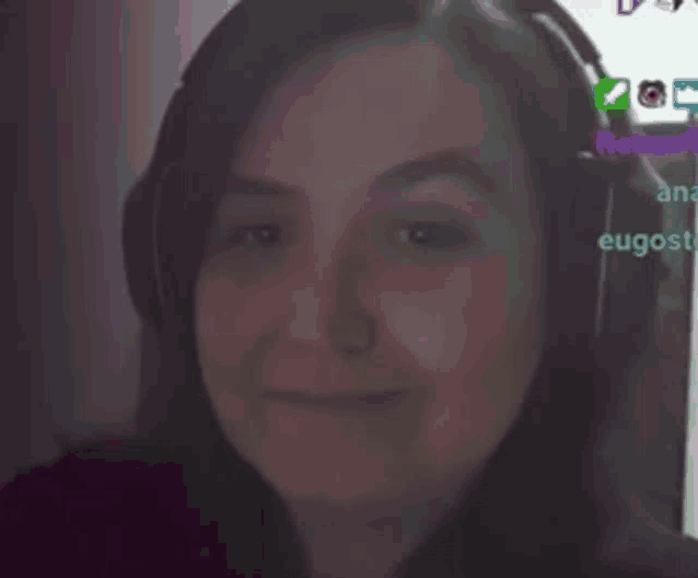 a woman wearing headphones is smiling in front of a computer screen