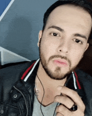 a man with a beard wearing a black leather jacket and a ring with the number 1 on it