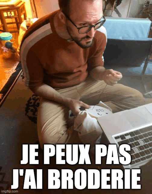 a man wearing glasses sits in front of a laptop with the words je peux pas j'ai broderie above him