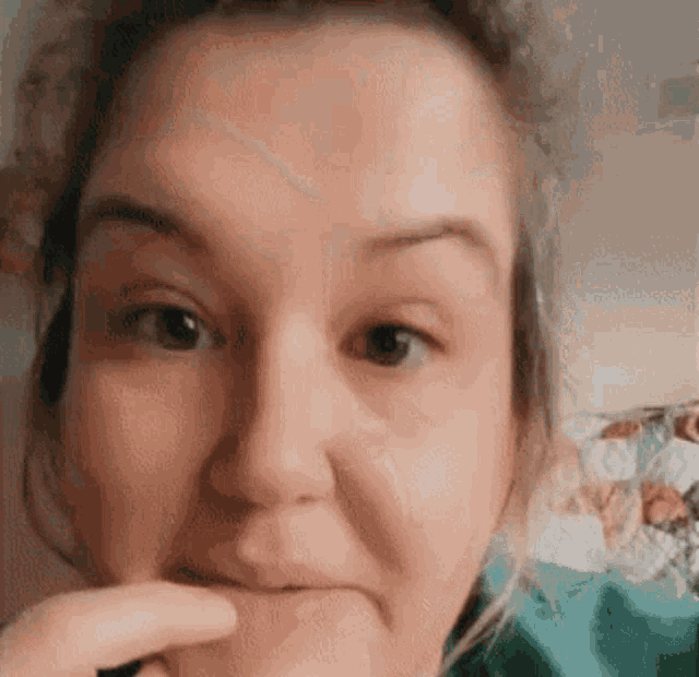 a close up of a woman 's face with her hand on her mouth