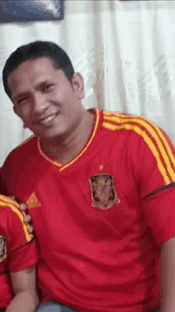 a man wearing a red and yellow adidas jersey