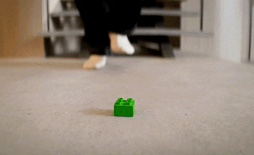 a green lego block is laying on the floor