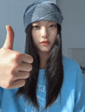 a woman wearing a blue shirt that says t3 on it gives a thumbs up