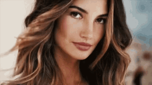 a close up of a woman 's face with her hair blowing in the wind