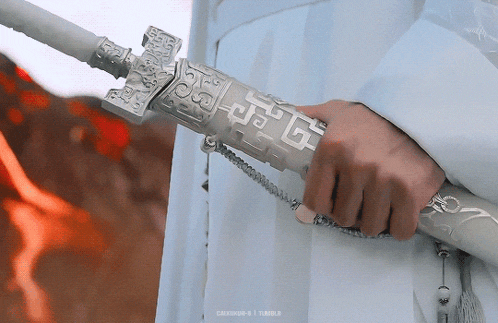 a person is holding a white sword in their hand .