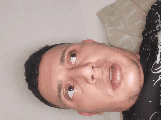 a man 's face is shown upside down with a pillow in the background with the letter g on it