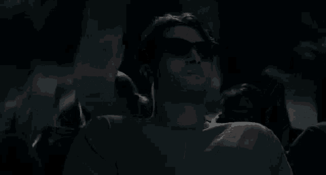 a man is watching a movie in a dark theater .