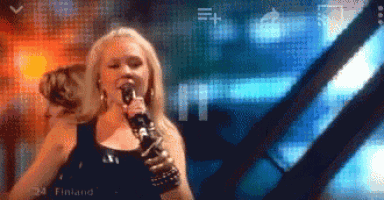 a woman singing into a microphone with the word finland in the background