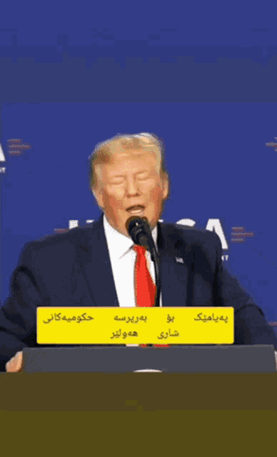 a man in a suit and tie is speaking into a microphone ..