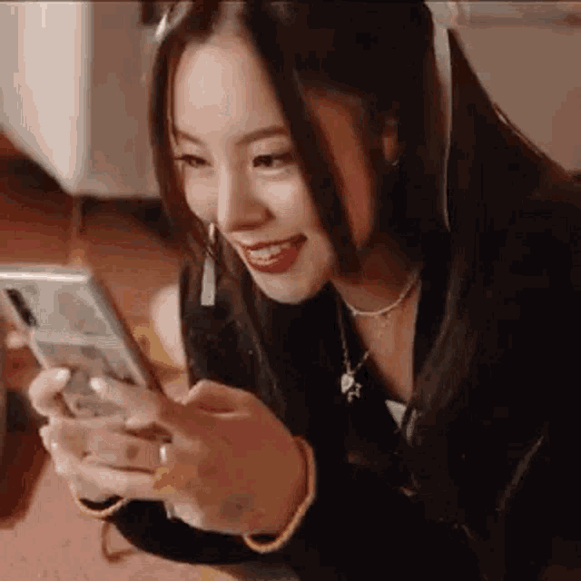 a young woman is sitting on the floor looking at her cell phone .