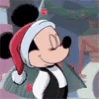 mickey mouse is wearing a santa hat and a tuxedo and smiling .