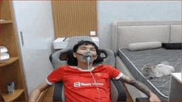 a man is sitting in a chair with an oxygen mask on his face in a bedroom .