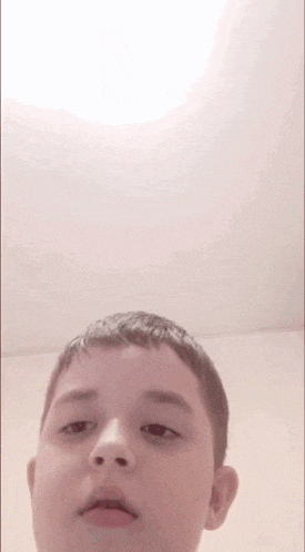 a young boy is making a funny face while looking up at the ceiling .