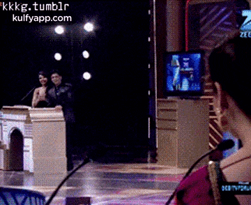 a woman sitting in front of a microphone with a screen behind her that says kkkg.tumblr