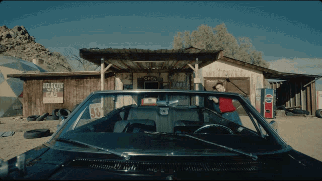 a car is parked in front of a building that says open on it