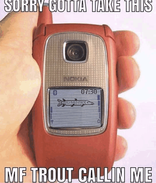 a person is holding a nokia flip phone with a fish on the screen