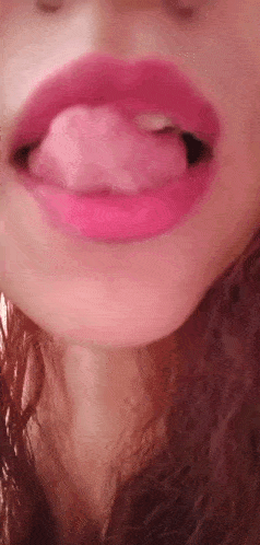 a close up of a woman 's mouth with pink lipstick sticking her tongue out .