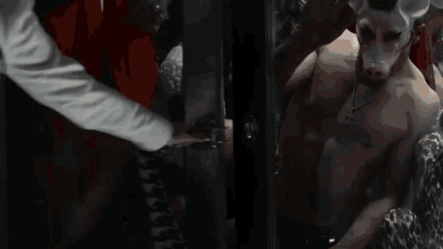 a man with a pig mask on his face is being held by a man in a red robe .