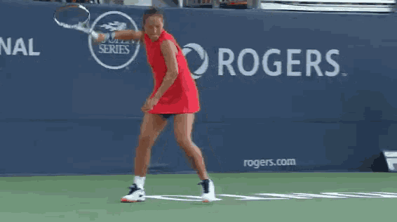 a woman is playing tennis in front of a rogers banner
