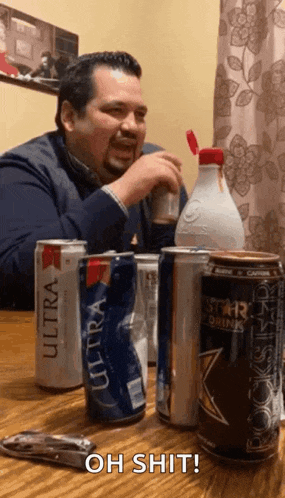 a man sitting at a table with cans of ultra and rockstar