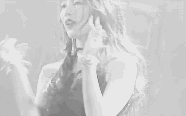 a black and white photo of a woman singing into a microphone while wearing bracelets .
