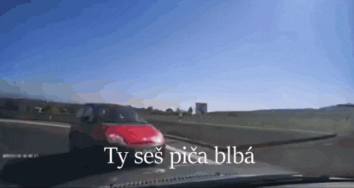 a red car is driving down a road with the words ty ses pica blba