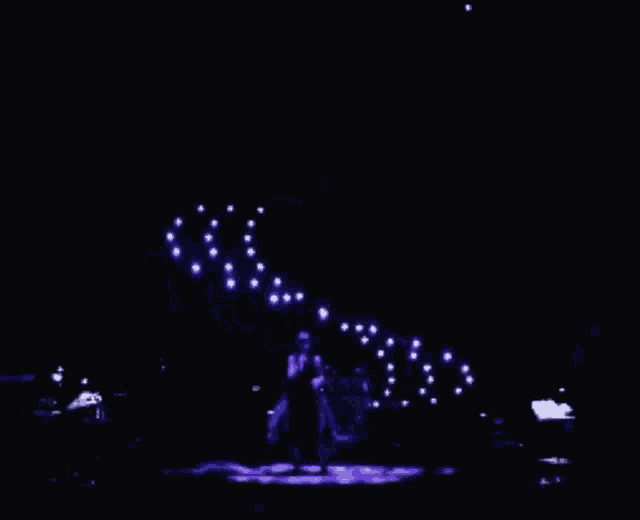 a man singing into a microphone on a stage in the dark
