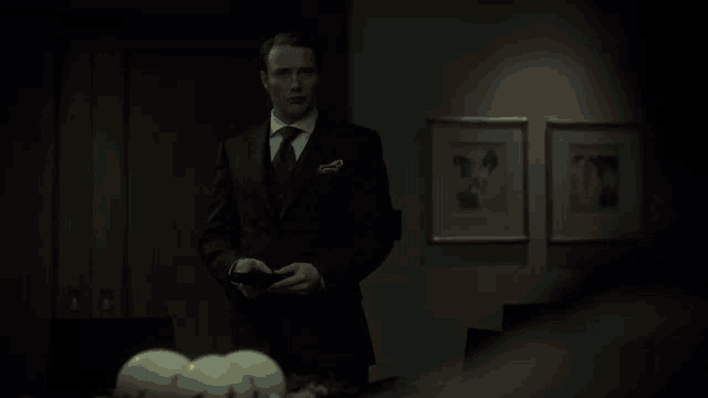 a man in a suit and tie is standing in a dark room and says i said it was mild