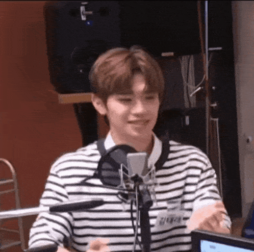 a young man is sitting in front of a microphone and smiling .