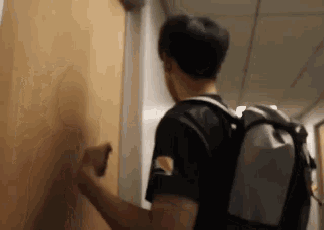 a man with a backpack is standing in a hallway .