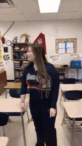 a cheerleader in a steve city uniform is standing in a classroom