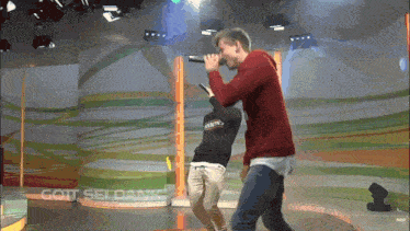 a man singing into a microphone while another man stands behind him with the words gott sei dank below him