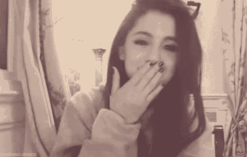 a black and white photo of a woman covering her mouth with her hands .